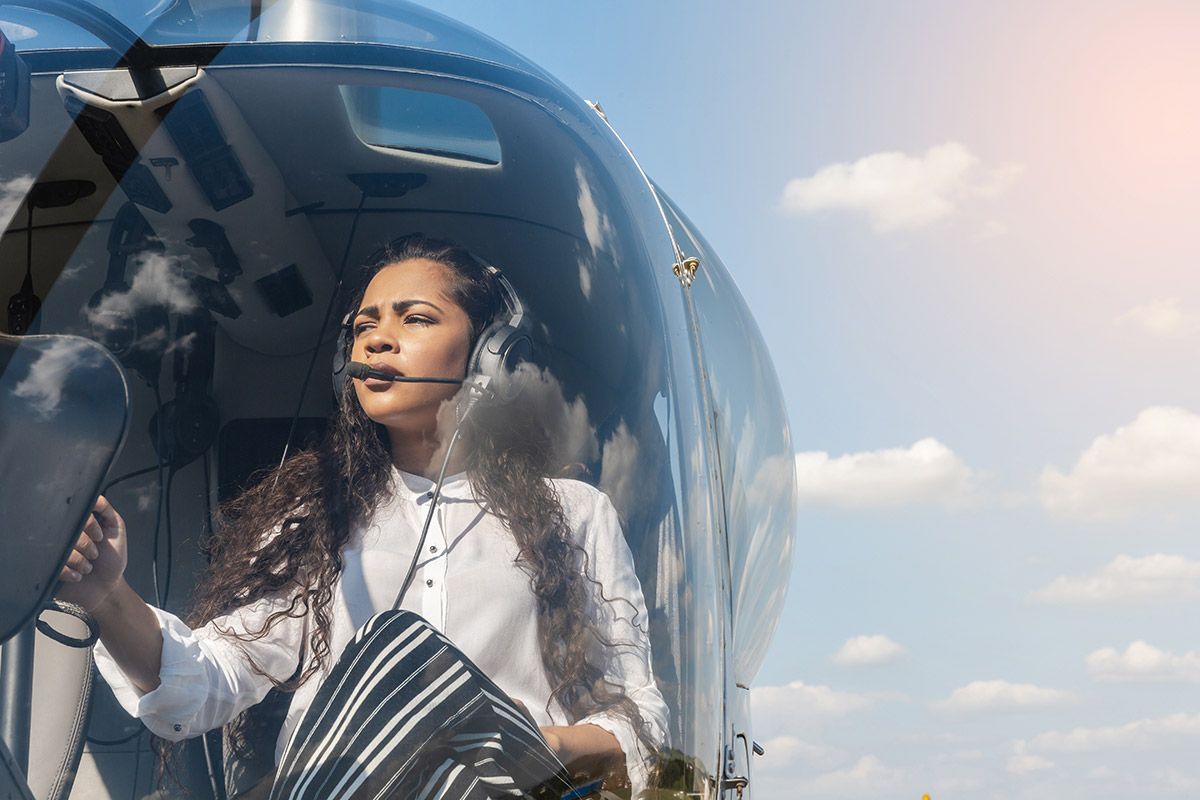 Female pilot in cockpit of helicopter before take off. Young woman helicopter pilot. Female pilot in cockpit of helicopter before take off. Young woman helicopter pilot.