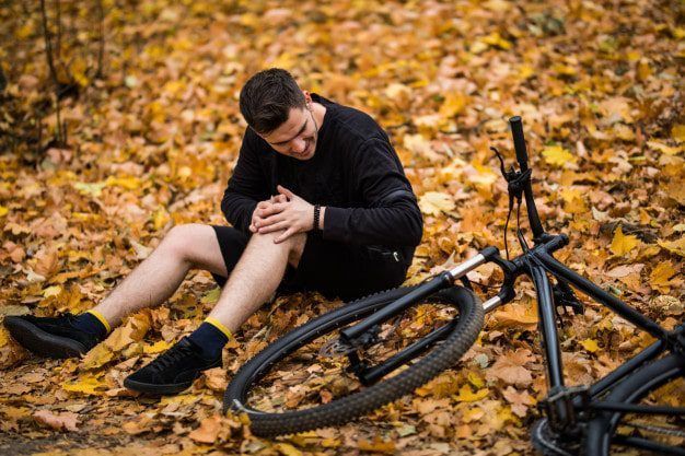hombre-joven-activo-que-sostiene-su-pierna-lastimada-o-rota-mientras-acostado-camino-bosque-otono-su-bicicleta_231208-959-min